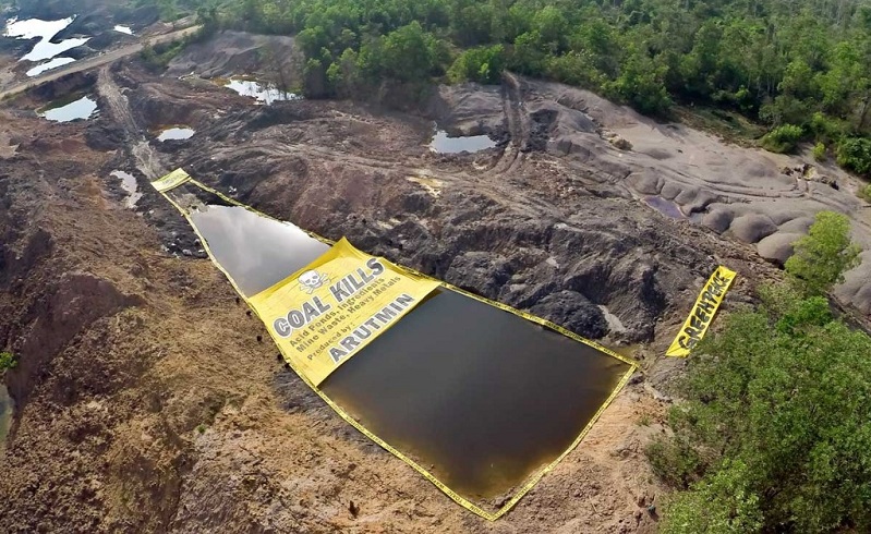 Aktivis Greenpeace melakukan aksi membentangkan peringatan bahaya air beracun di bekas pengerukan tambang batubara, Asam-Asam, Kalimantan Selatan. (dok. greenpeace)